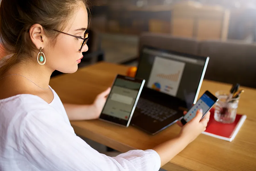 Woman with phone, tablet, and laptop.